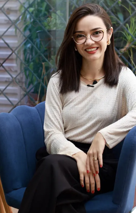 Dra. Andressa Hirako sorrindo, sentada no consultório
