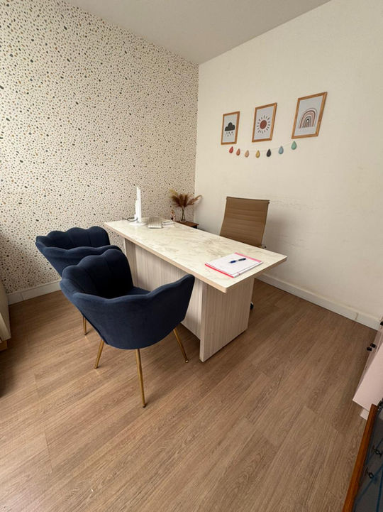 Sala de atendimento com mesa de consulta e poltronas para os pais