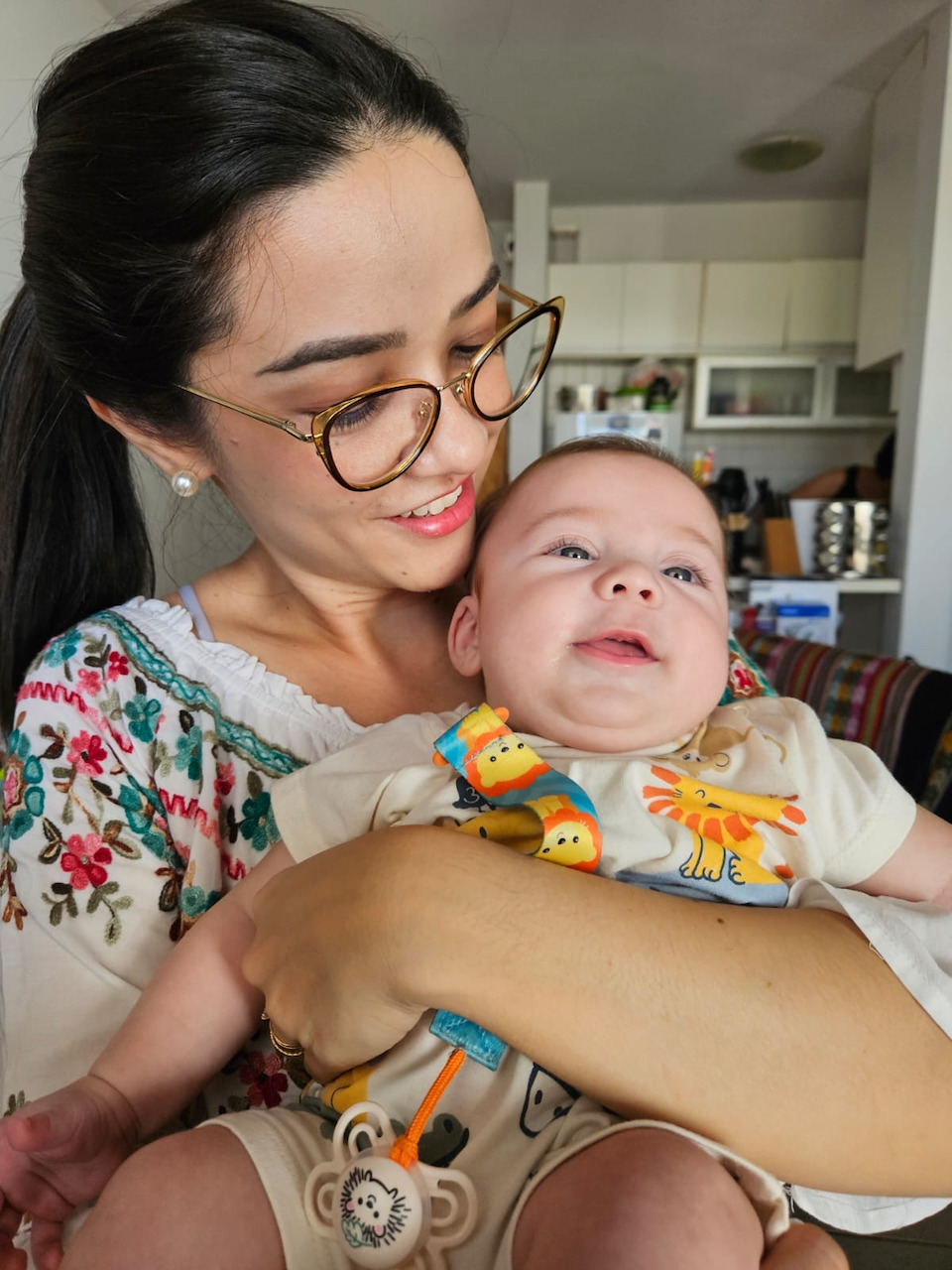 Dra. Andressa aproxima um bichinho de pelúcia do rosto de um bebê durante atendimento domiciliar
